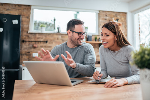 Positive young couple looking at laptop and talking.