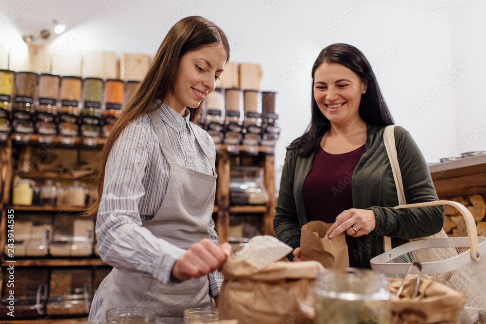 Friendly shopkeeper scooping flour for customer in packaging free shop. Friendly shopkeeper scooping flour for customer in packaging free shop.