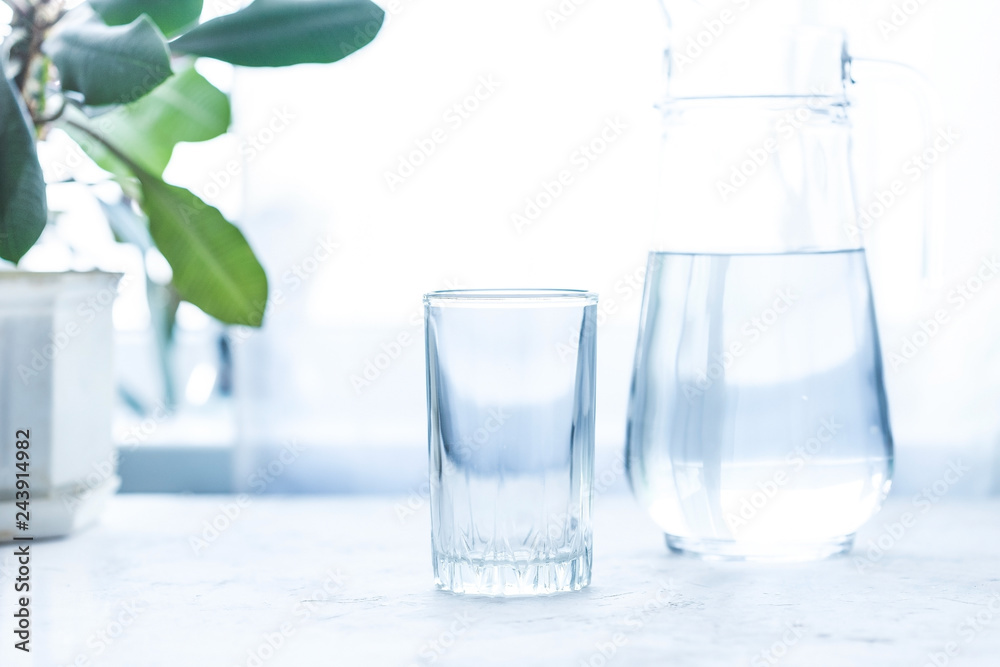 glass cup and carafe with water on a white table glass cup and carafe with water on a white table