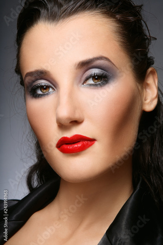 Portrait of young beautiful brunette with smoky eye make-up and red lips