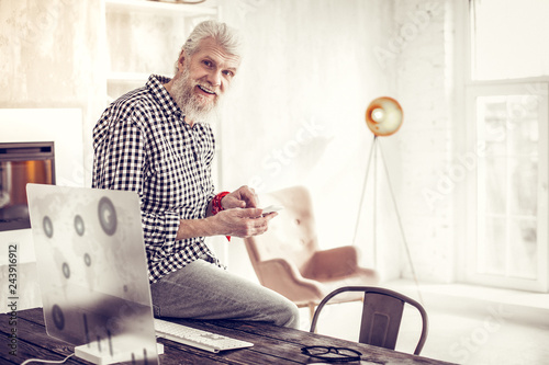 Positive delighted mature male sitting on the table photo