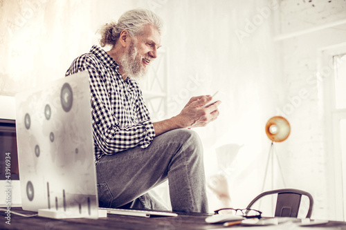 Kind bearded man looking at screen of his gadget photo