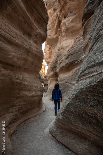 Woman hiking in the Beautiful American Canyon Landscape during a sunny evening. Taken in Kasha-Katuwe Tent Rocks National Monument, New Mexico, United States.