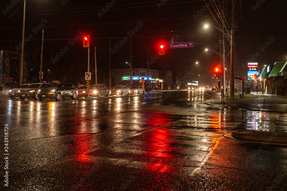 Fototapeta premium Toronto, CANADA - December 4th, 2019: Dramatic rainy night with empty streets and reflecting traffic lights in city suburbia roads