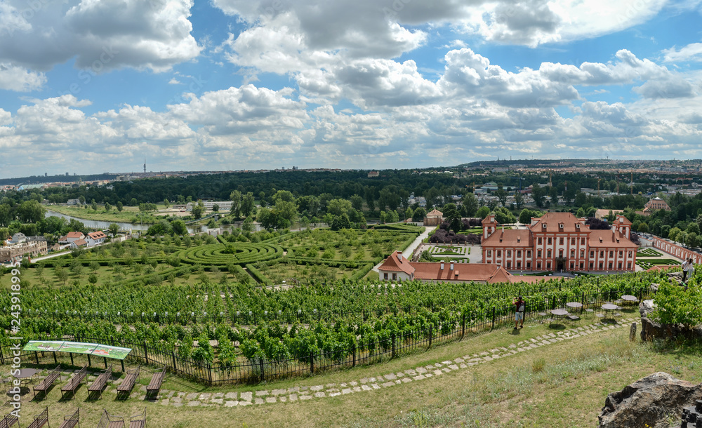 Panorama. The sky, green vineyards and a magnificent palace - Troja Castle. Prague surprises with its landscapes and views. In the distance there is a green labyrinth and red roofs of this ancient cit