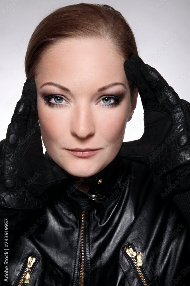 Beautiful woman in black leather biker's jacket and gloves with smoky eye makeup Beautiful woman in black leather biker's jacket and gloves with smoky eye makeup