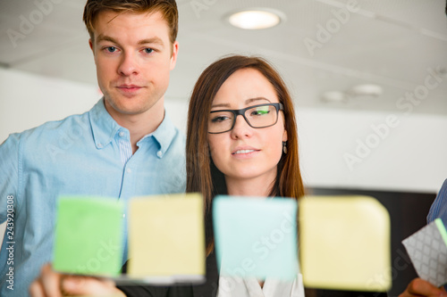 Businesswoman And Colleague Looking At Notes Stuck On Glass © kjekol
