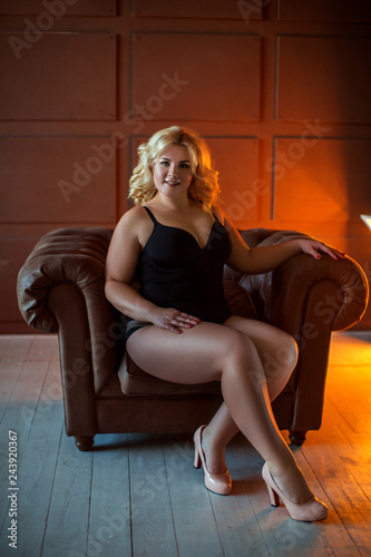 Beautiful girl in sexy black underwear sits in luxurious leather chair