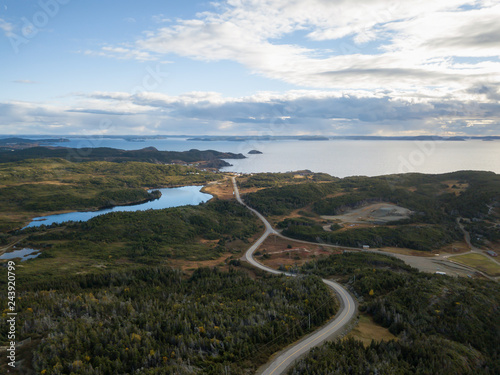 Aerial view of a scenic road on a rocky Atlantic Ocean Coast during a cloudy sunset. Taken in Twillingate, Newfoundland, Canada.