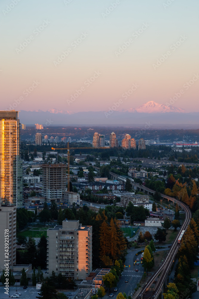 Aerial view of a modern city with Mount Baker in the Background during a vibrant sunset. Taken in Metrotown, Burnaby, Vancouver, BC, Canada.