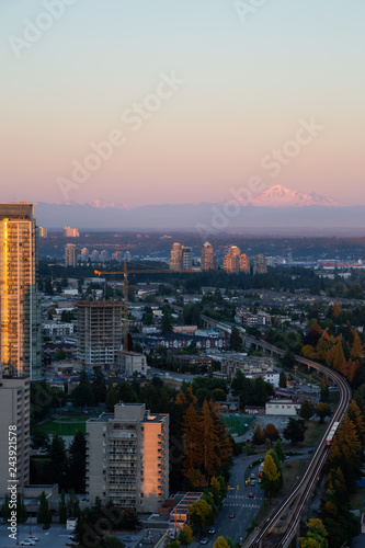 Fototapeta Naklejka Na Ścianę i Meble -  Aerial view of a modern city with Mount Baker in the Background during a vibrant sunset. Taken in Metrotown, Burnaby, Vancouver, BC, Canada.