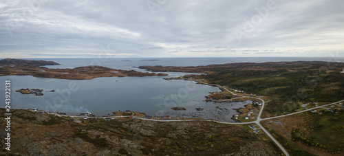 Aerial panoramic view of a small town on a rocky Atlantic Ocean Coast during a cloudy day. Taken in Little Quirpon, Newfoundland, Canada. photo