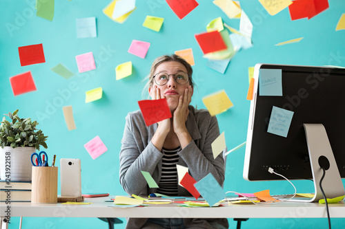 Stressed young business woman looking up surrounded by post-its in the office. photo