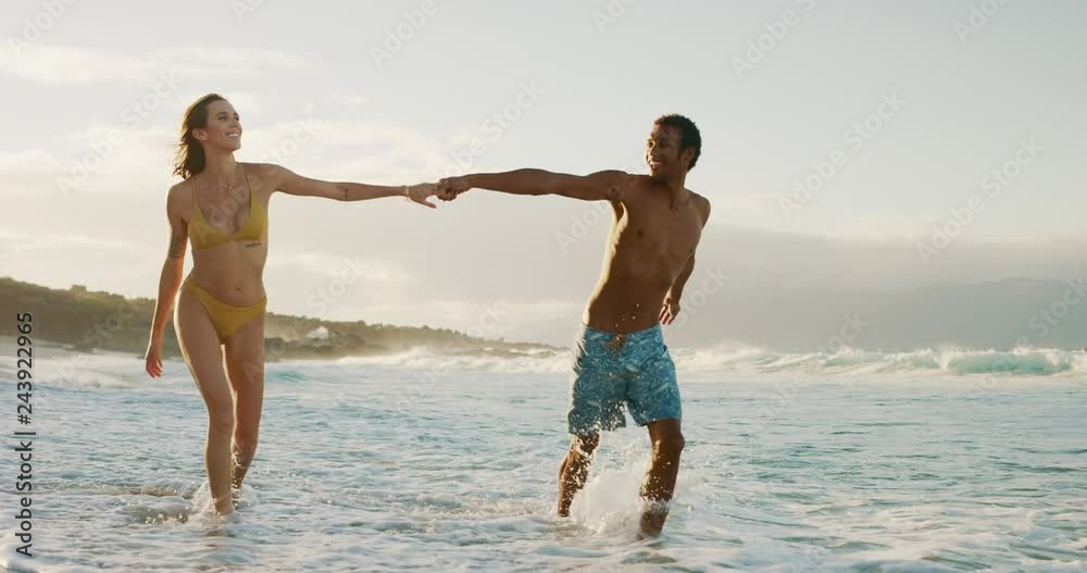 Happy young couple enjoying golden sunset playing on the beach, mixed race Happy young couple enjoying golden sunset playing on the beach, mixed race