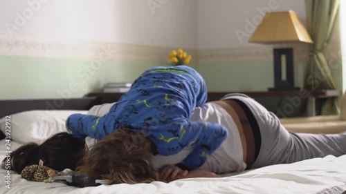 Two brothers in pajamas fighting playing and fooling around on the bed in the bedroom in the morning. photo