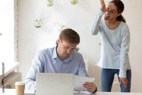 Εκτύπωση καμβά Disrespectful female employee, student grimacing, standing behind back of seriou
