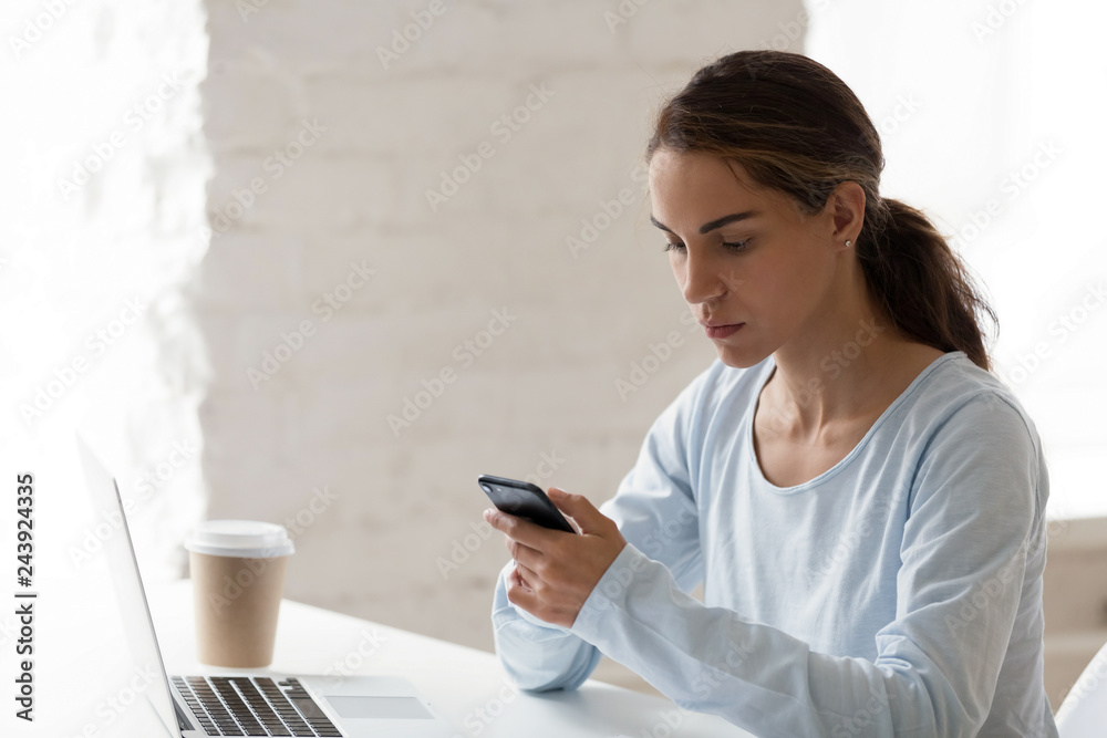 Serious focused woman using phone at workplace, reading message, smartphone looking at screen, checking email or social networks, call to client or customer, browsing mobile device app Serious focused woman using phone at workplace, reading message, smartphone looking at screen, checking email or social networks, call to client or customer, browsing mobile device app