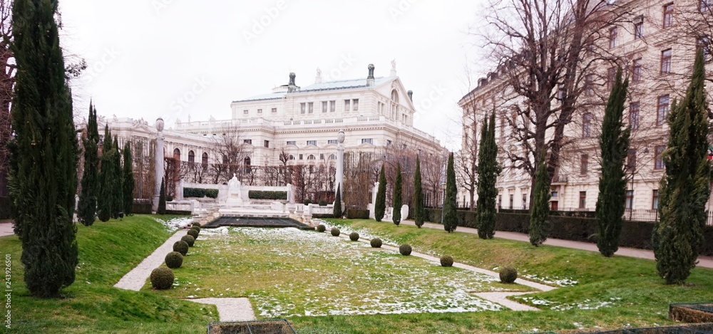 Obraz premium Winter park with a frozen fountain and sculptures in Vienna. In the distance you can see the Hofbroek building.
