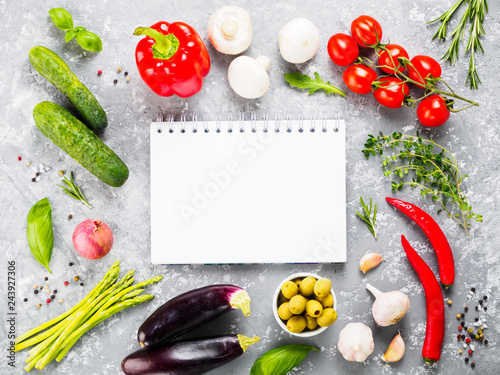 Fototapeta Naklejka Na Ścianę i Meble -  Notebook and ingredients for cooking vegetables and herbs on gray concrete background. Top view. Copy space. Cooking concept. Mockup