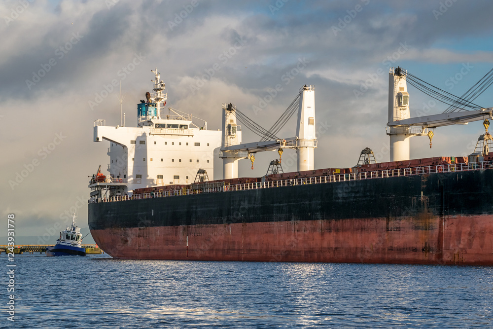 Cargo ship being docked by Tug Boat