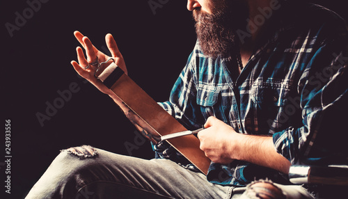 Man stropping straight razor with leather tool. Vintage tools for barbers, razor, sharpen the blade in leather brush, razor blades. Straight razor. Straight razors, barbershop, beard, blade.