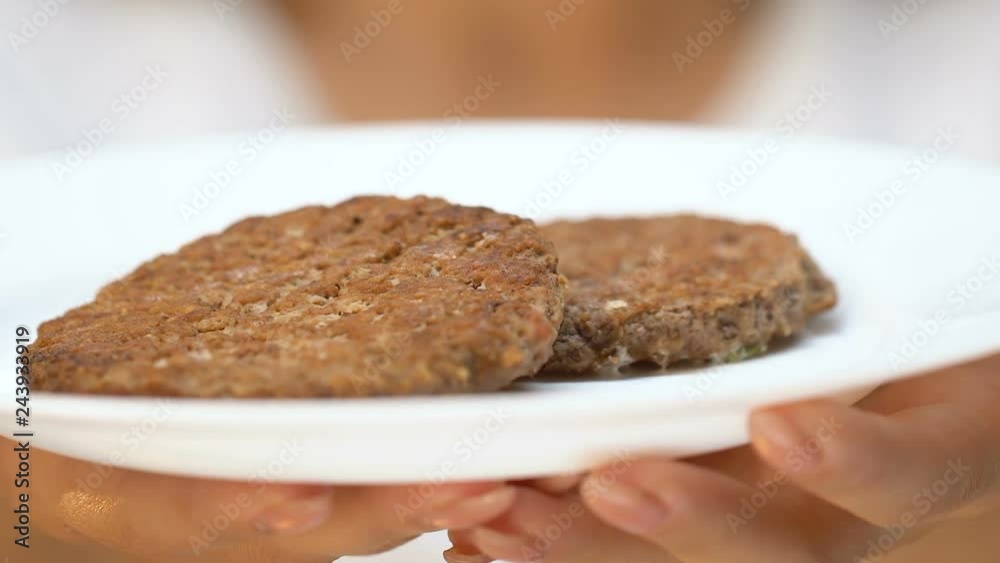 Woman showing fatty patty to camera, unhealthy diet and junk food addiction Woman showing fatty patty to camera, unhealthy diet and junk food addiction