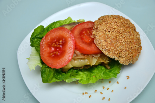 Gesundes Sandwichbrötchen mit Cheeseburger, gebratenen Zwiebeln und Tomatenscheiben