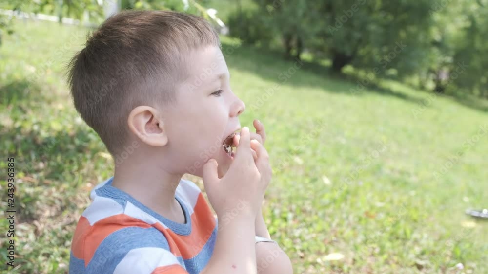 Cute Little Kid boy outdoors eating a sandwich Cute Little Kid boy outdoors eating a sandwich