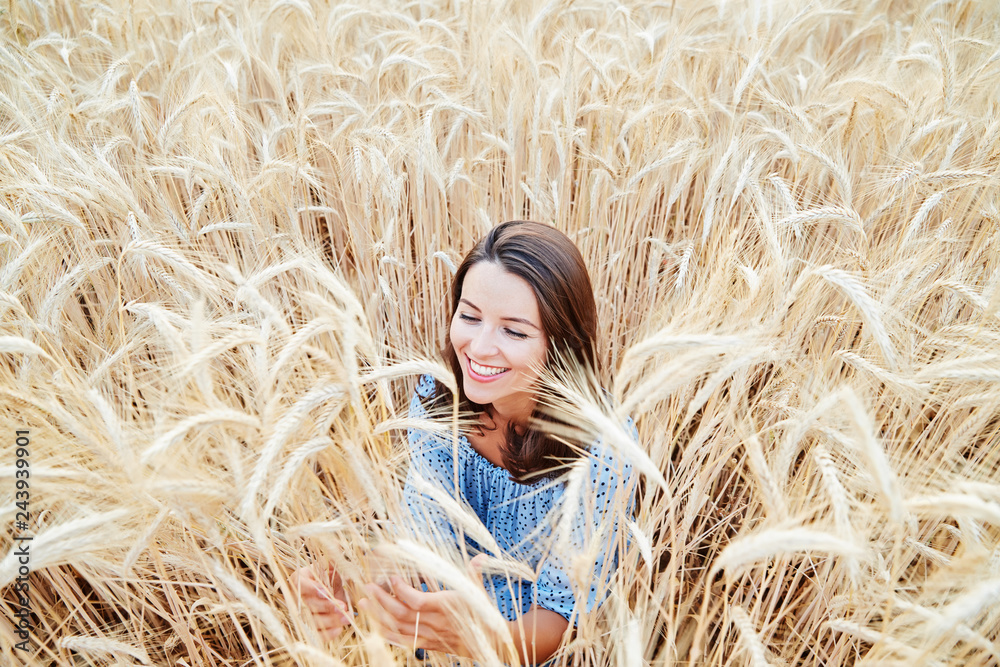 The beautiful young girl with long brunette hairs poses in the field with wheat, sunset light, turns, smiles, flirts, happy, blue dress, France, Provence The beautiful young girl with long brunette hairs poses in the field with wheat, sunset light, turns, smiles, flirts, happy, blue dress, France, Provence