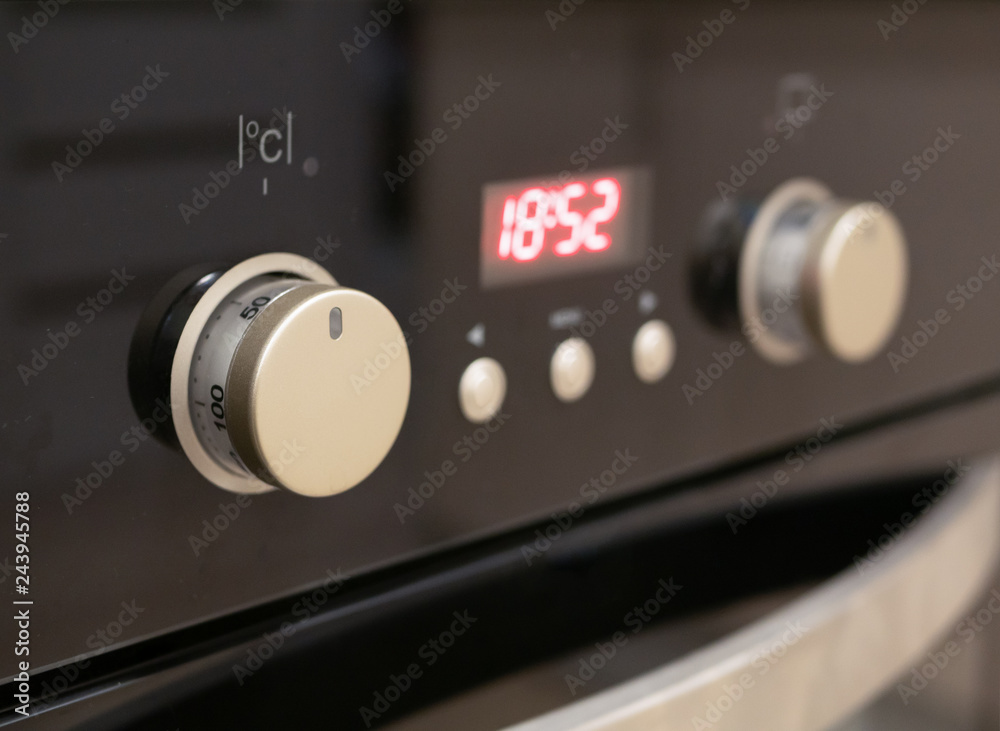 closeup of control dials and buttons of modern kitchen oven. selective focus on closest knob with blurred digital display closeup of control dials and buttons of modern kitchen oven. selective focus on closest knob with blurred digital display