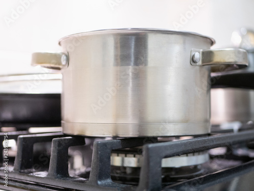 closeup of shiny stainless steel saucepan on kitchen stove burner grid