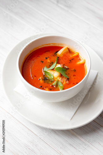 tomato soup with smoked meat in a white bowl on a wooden white background, Italian cuisine