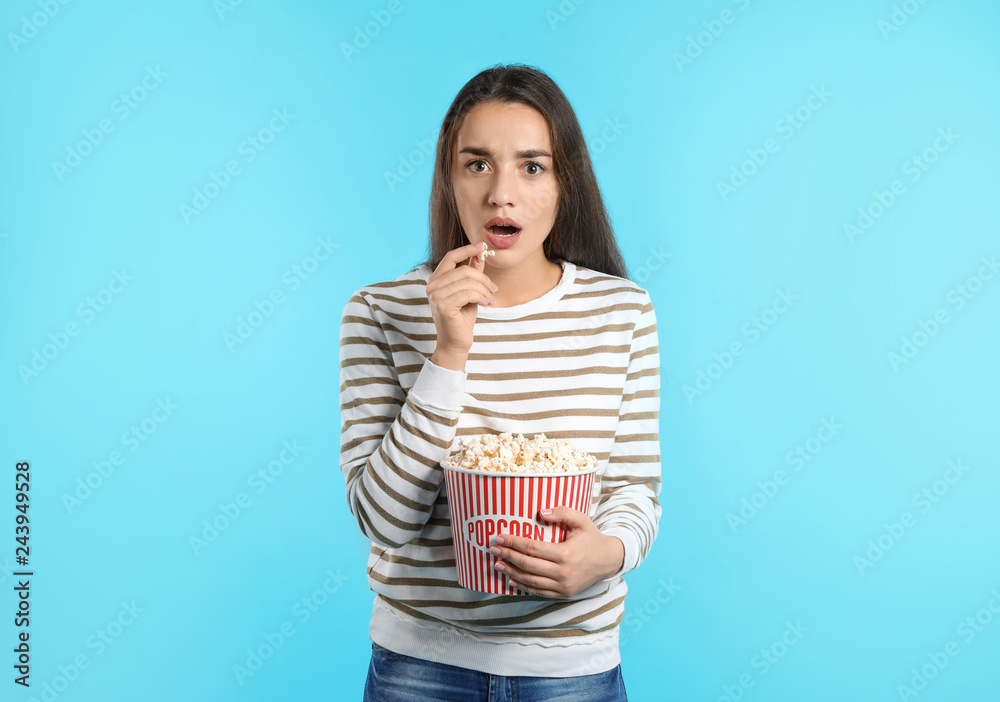 Fototapeta premium Emotional woman with popcorn during cinema show on color background