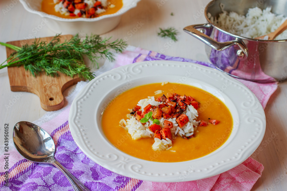 Healthy vegan pumpkin cream soup with rice, apples, roasted carrots and fresh herbs