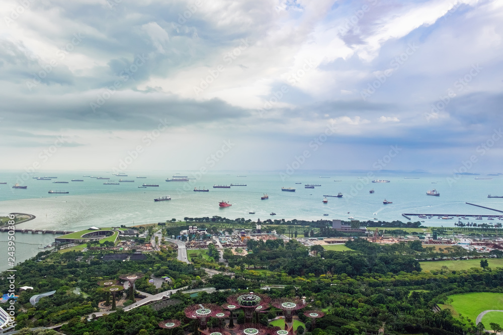 Singapore harbor with many ships and boats is seen from Marina Bay Sands hotel view point in a cloudy day