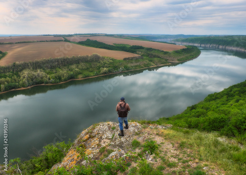 tourist on a cliff above the canyon. person on a cliff above the picturesque river. spring dawn 