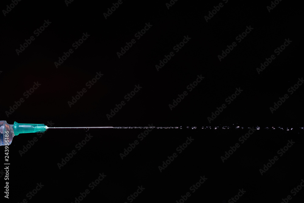 syringe on a dark background. a drop on the tip of the needle syringe on a dark background. a drop on the tip of the needle