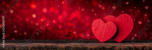 Two Red Valentine's Hearts Standing On Wooden Table With Soft Romantic background