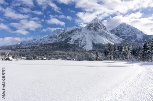 Winter mountain landscape with groomed ski trails and blue sky with white clouds in sunny day. Ehrwald valley, Tirol, Alps, Austria. © msnobody