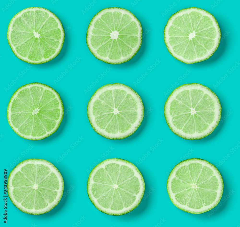 Fototapeta premium Fruit pattern of lime slices on blue background. Flat lay, top view.