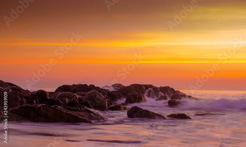 Warm vibrant orange sunset over the rocks in water of ocean and sea background wallpaper. Concept of beautiful evening. Long exposure. Portugal, Porto area