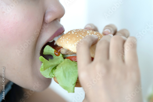 Young woman eating home made burger.