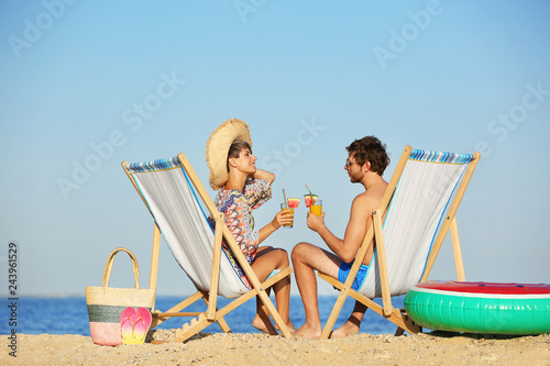 Young couple with cocktails in beach chairs at seacoast © New Africa