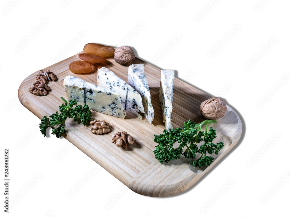 Some peaces of the cheese blue mold roquefort  with dried apricot and peaces of the nuts with parsley at the wooden desk and background