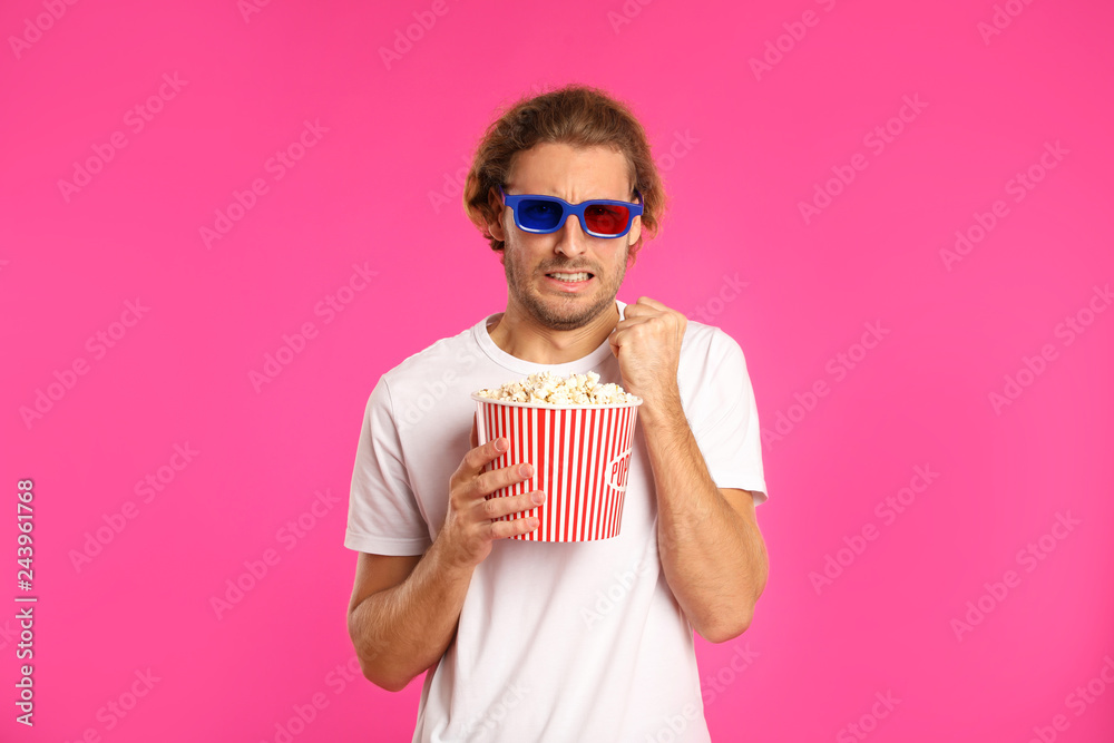 Emotional man with 3D glasses and popcorn during cinema show on color background Emotional man with 3D glasses and popcorn during cinema show on color background
