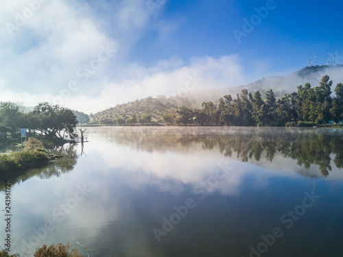 An idyllic landscape, Caren Lagoon during Winter Season, a colorful mirror over the waters with amazing cloud reflections with the trees foliage in the forest on a misty day with a moody atmosphere