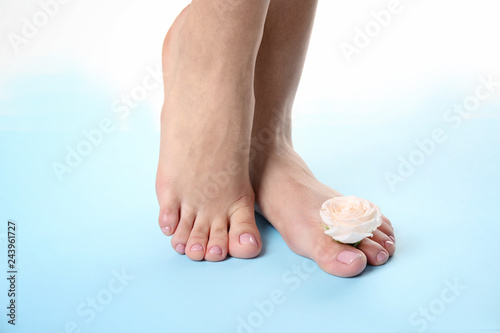 Woman with smooth feet  and flower on color background, closeup. Spa treatment