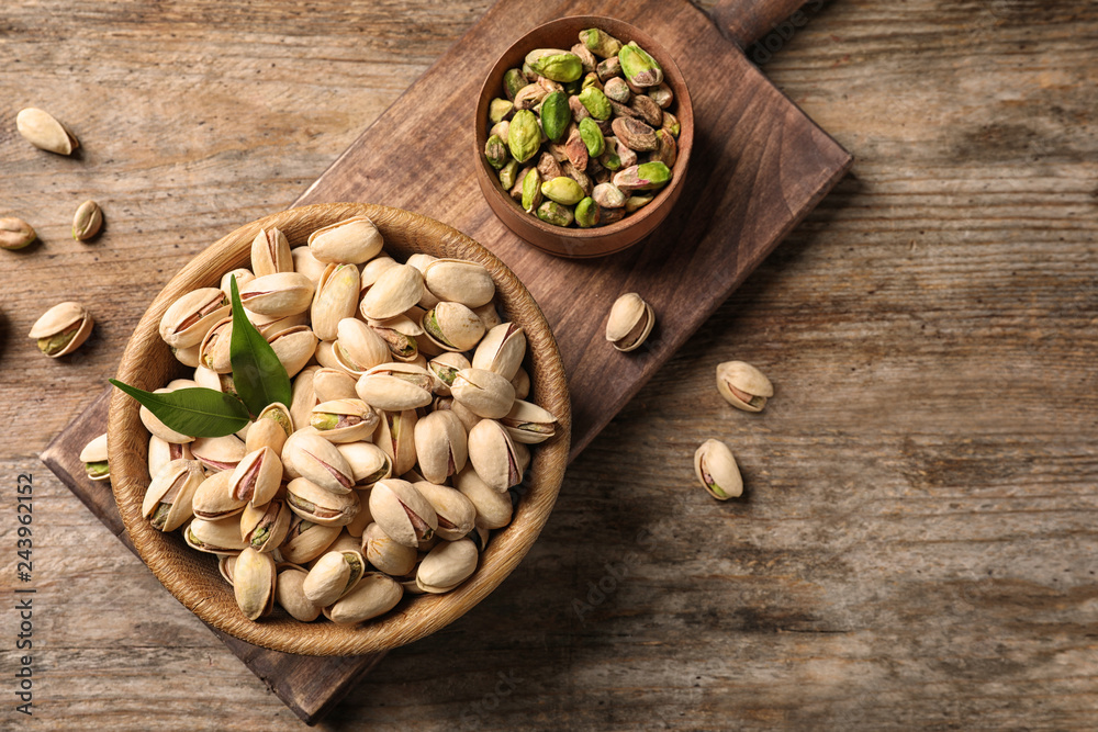 Organic pistachio nuts in bowl on wooden table, flat lay. Space for text Organic pistachio nuts in bowl on wooden table, flat lay. Space for text