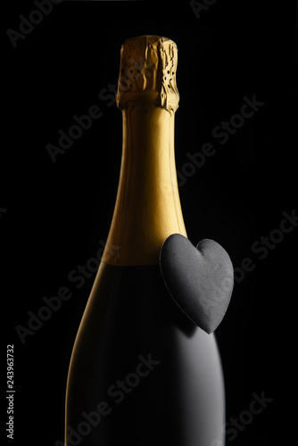 Closeup of a bottle of Champagne with a black heart against a black background