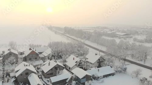 Drone 4K aerial footage of village in the plain covered with snow. White cloudy winter weather.